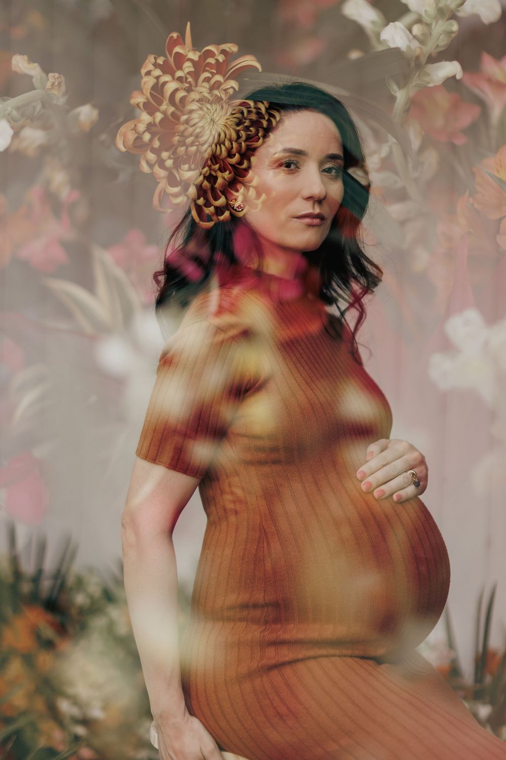 Dreamy maternity photo featuring a rustic orange dress against a floral backdrop with soft double exposure effects.