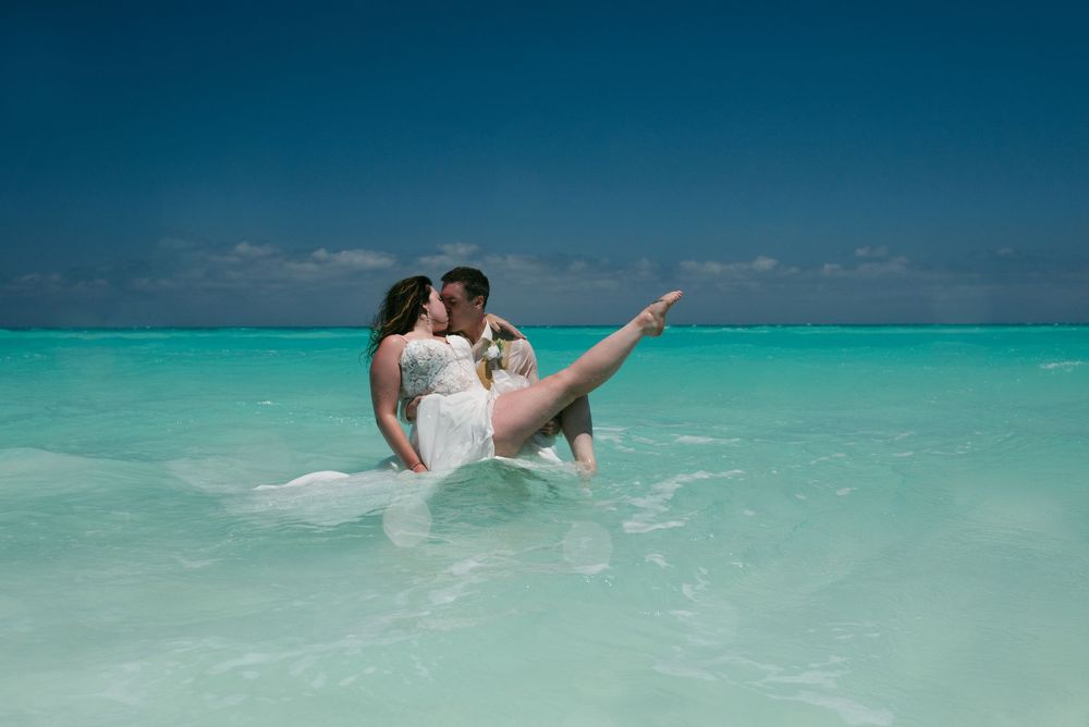 A couple embraces in crystal clear turquoise waters on a tropical beach.