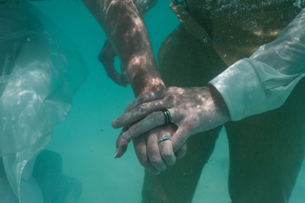 Underwater view of legs and feet in shallow turquoise ocean water.