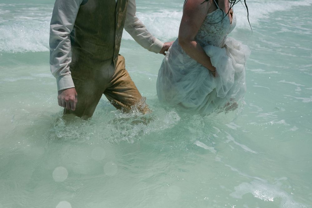 People wading in shallow tropical waters wearing casual clothing.
