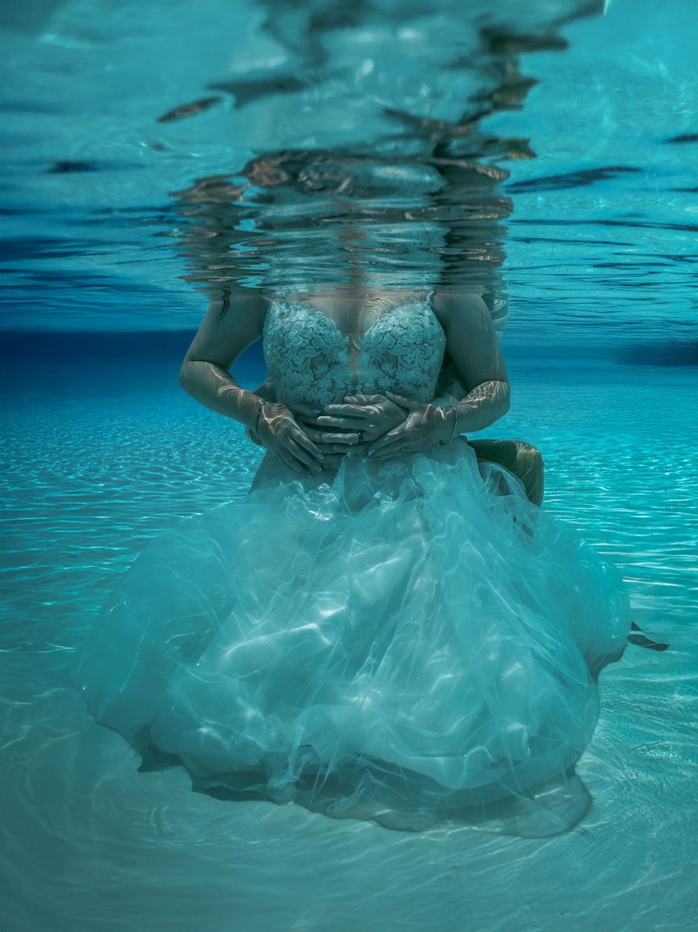 Underwater photography showing flowing white fabric in crystal blue water.
