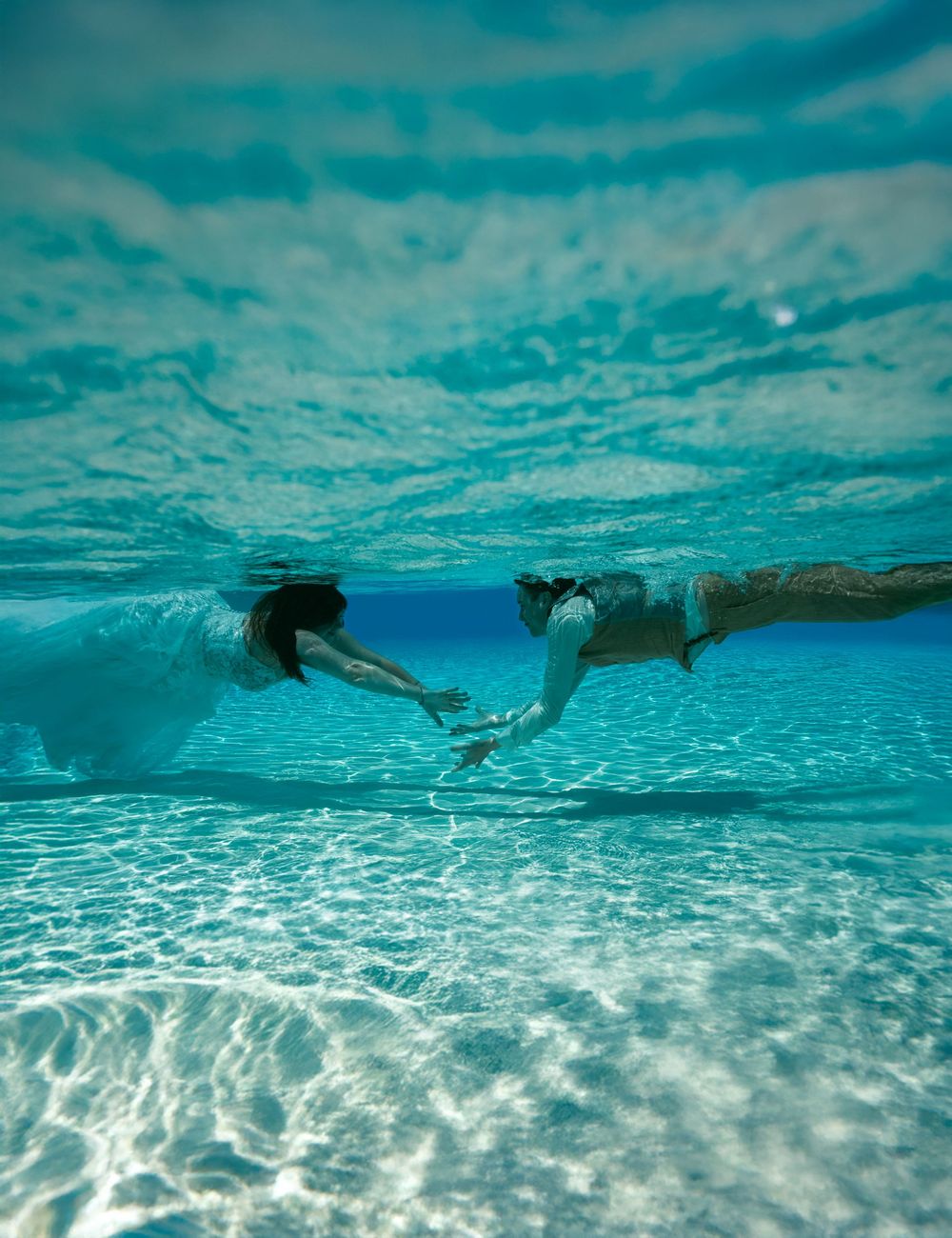 Underwater view of sandy ocean floor with rippled sunlight patterns.