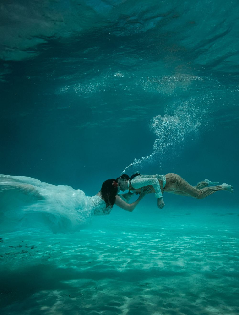 Underwater scene of swimmers gliding through crystal clear tropical waters.