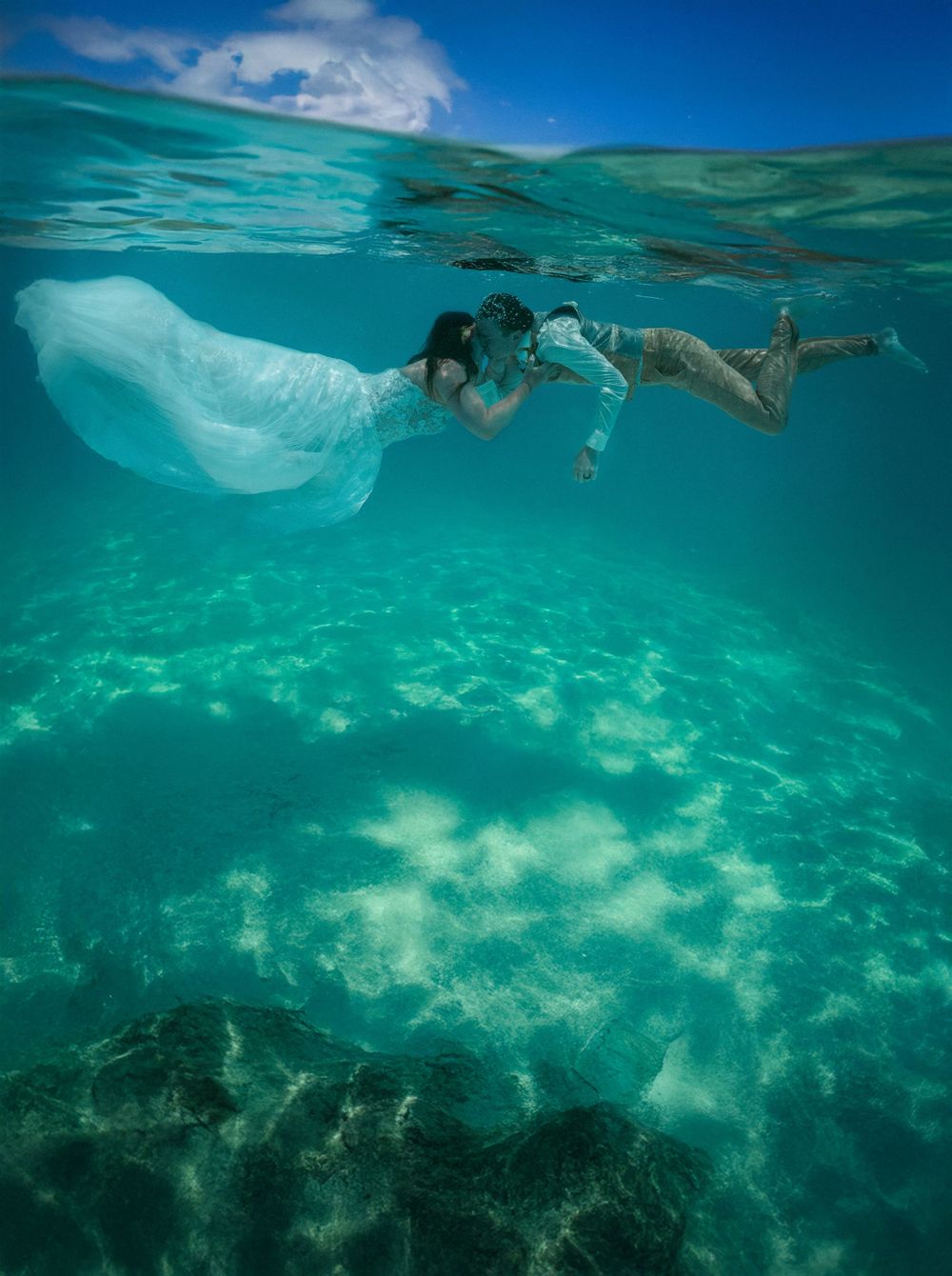 Split-shot photograph showing both above and below water in a tropical ocean setting.