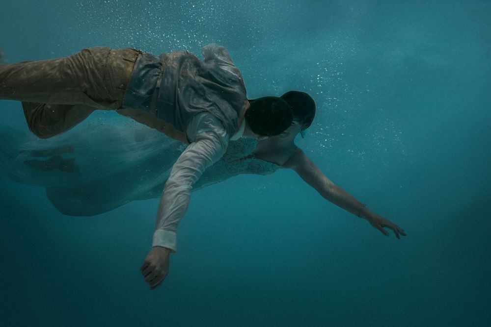 Underwater photography capturing swimmers in flowing motion through turquoise waters.