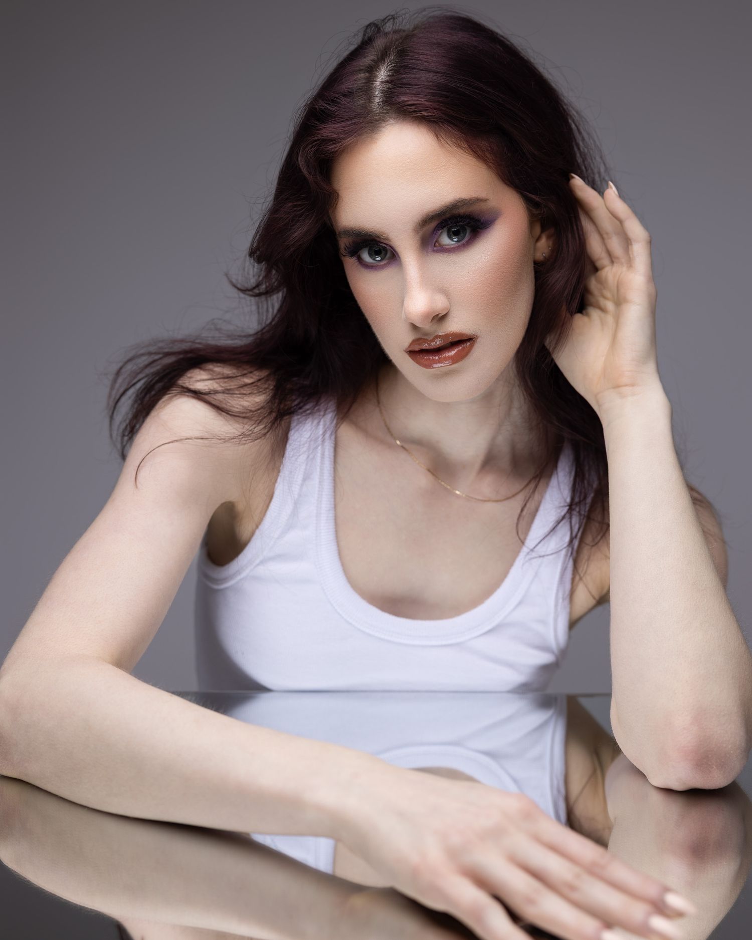 Professional beauty portrait of model in a white tank top with smoky eye makeup and burgundy lipstick in a Brampton studio setting.
