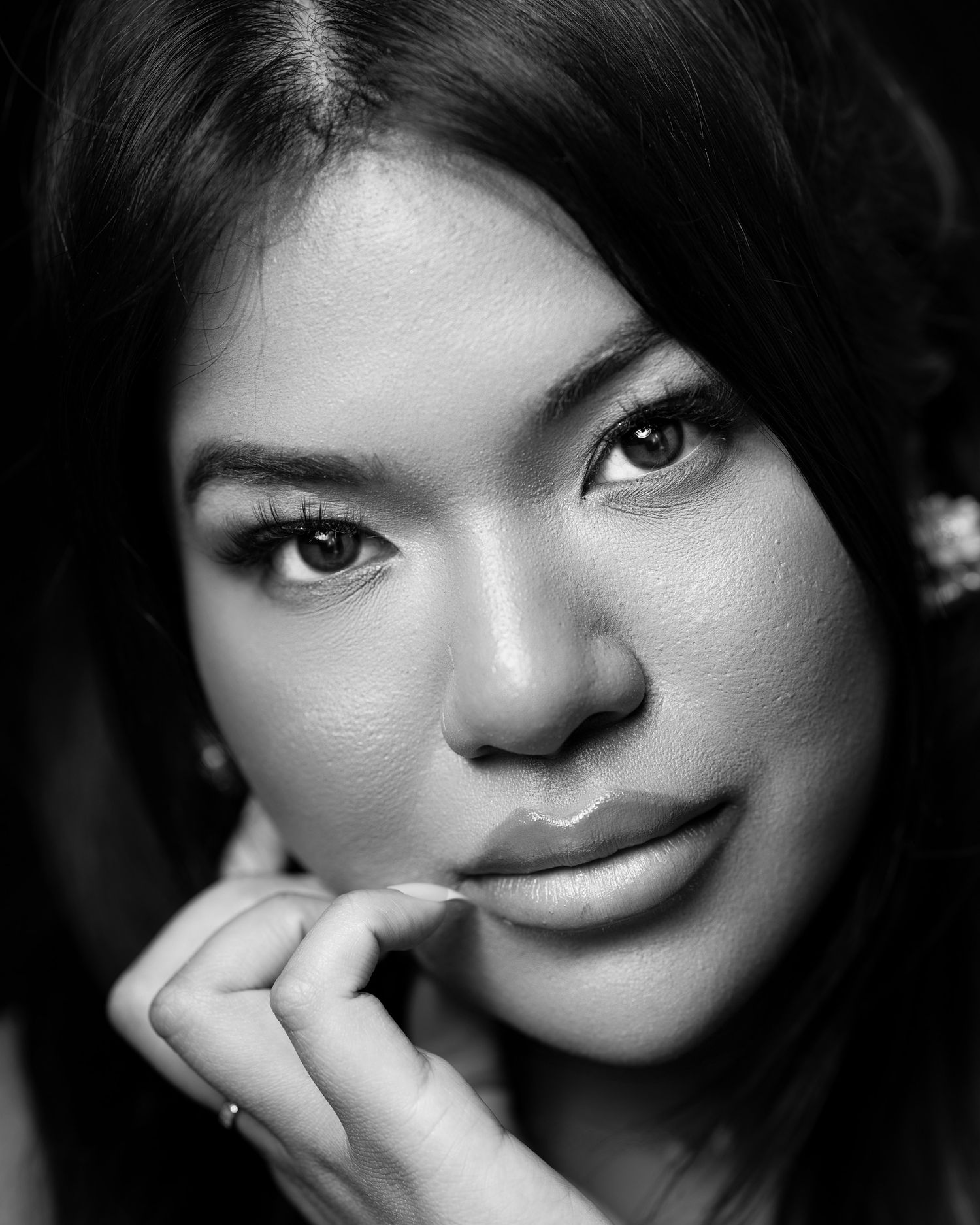 Black and white portrait showing a contemplative expression with hand resting near chin in dramatic lighting.