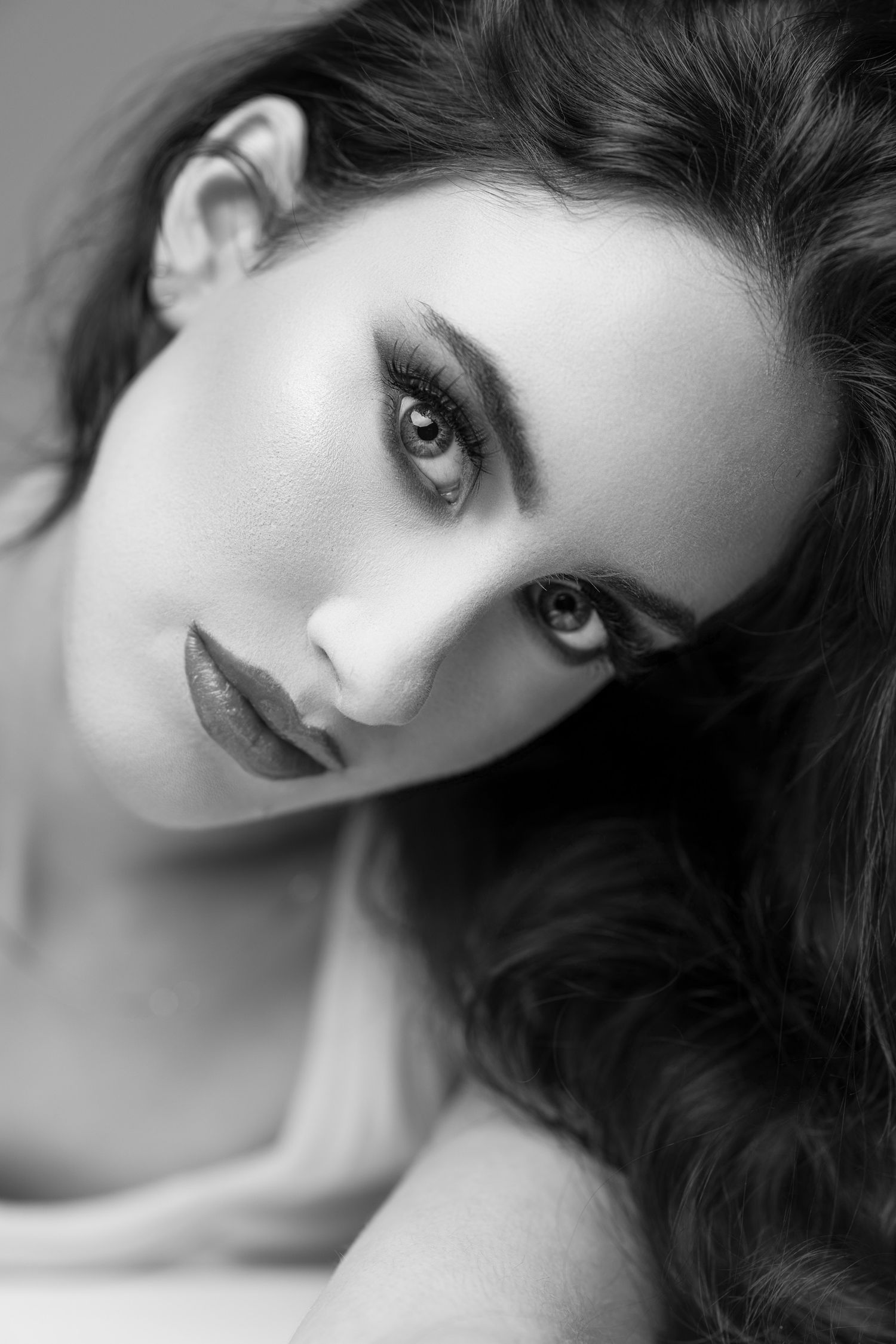 Black and white artistic portrait showcasing dramatic eye makeup and flowing dark hair in an elegant pose in Toronto portrait studio.