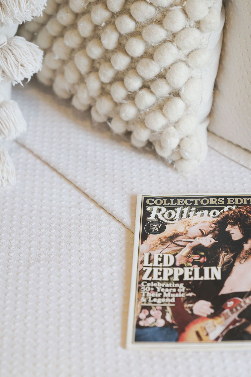 Vintage Led Zeppelin Rolling Stone magazine beside white pom pom textured pillow.