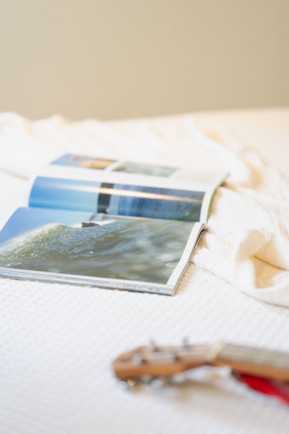 Travel photo book laying open on white textured bedding.