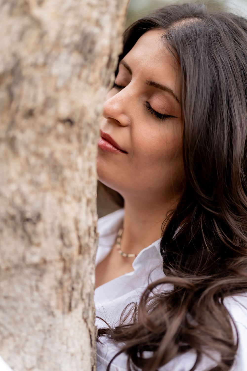 Profile view of styled dark wavy hair against textured stone background.