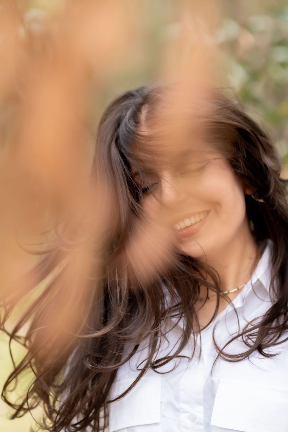 Artistic blurred portrait showing flowing dark hair and joyful expression.