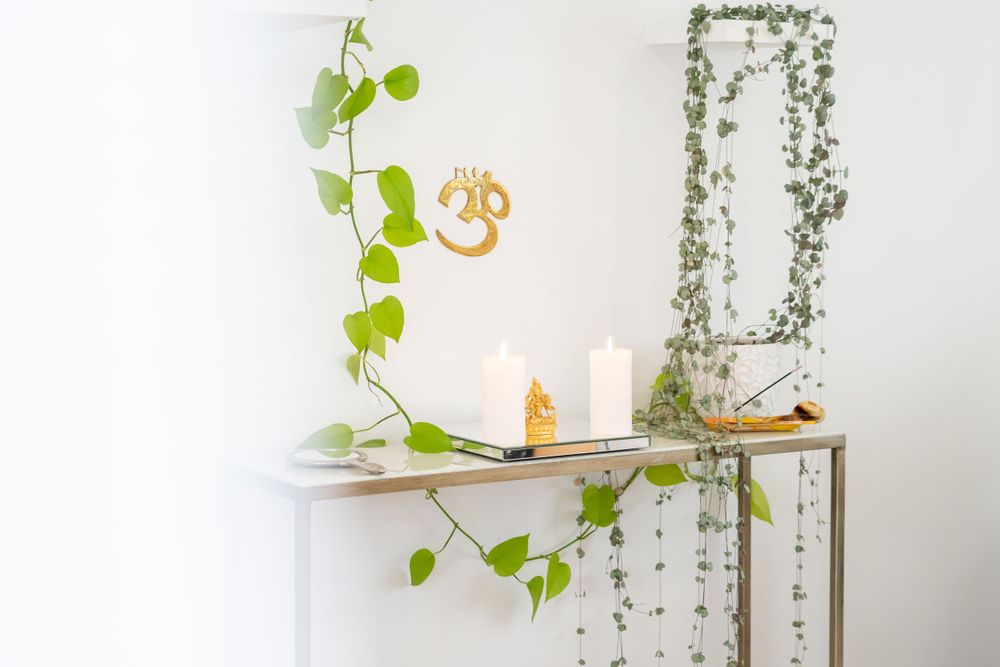White shelf decorated with climbing vines, candlesticks and an om symbol in a serene spa setting.