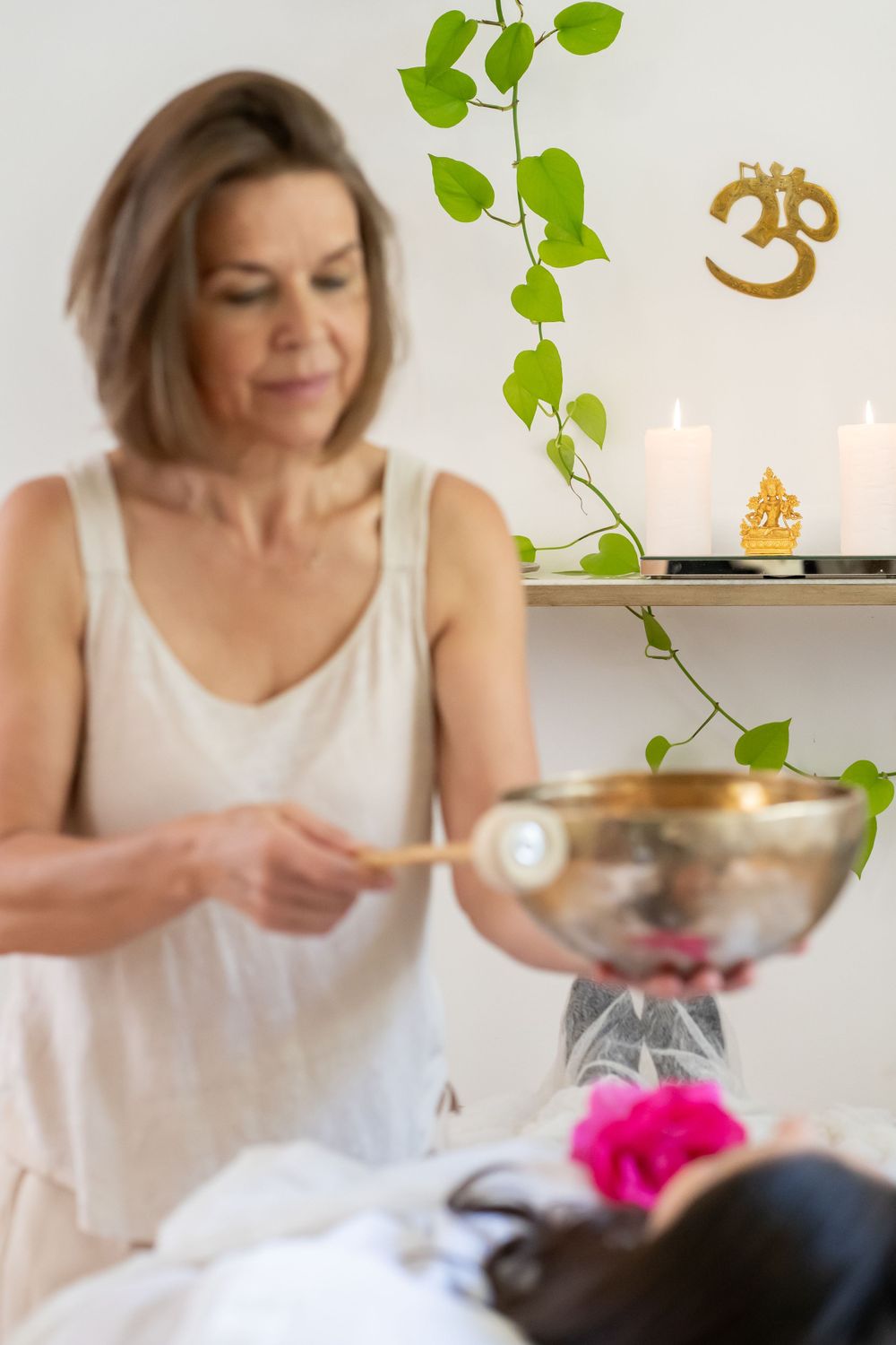 A therapist performing a wellness treatment in a serene spa setting with plants and candles.