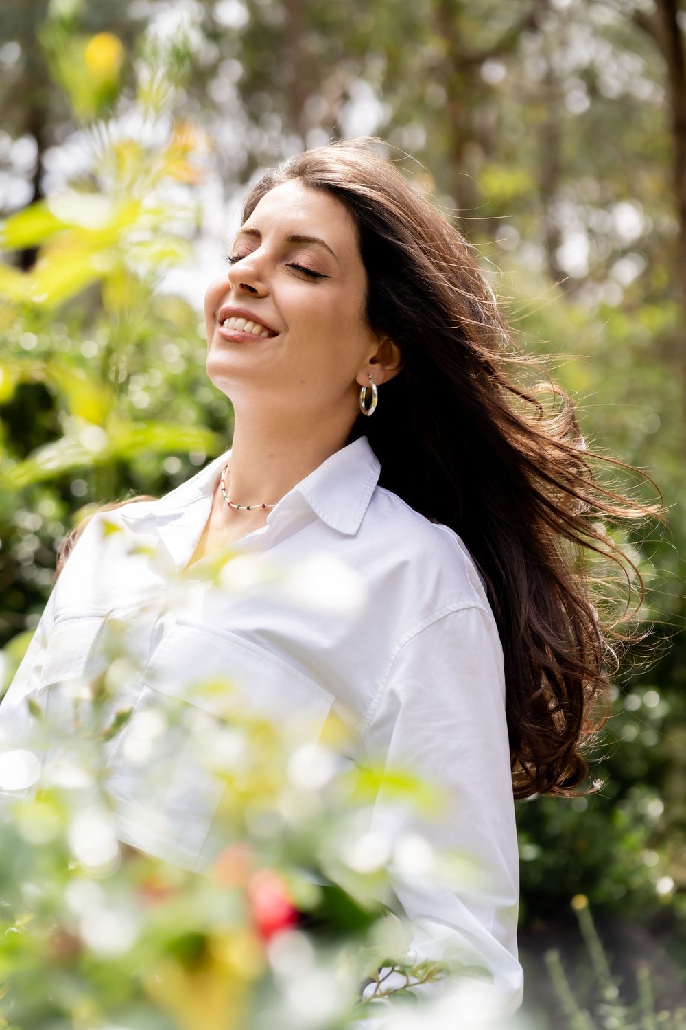 A joyful moment captured outdoors with sunlight filtering through leaves and flowers.
