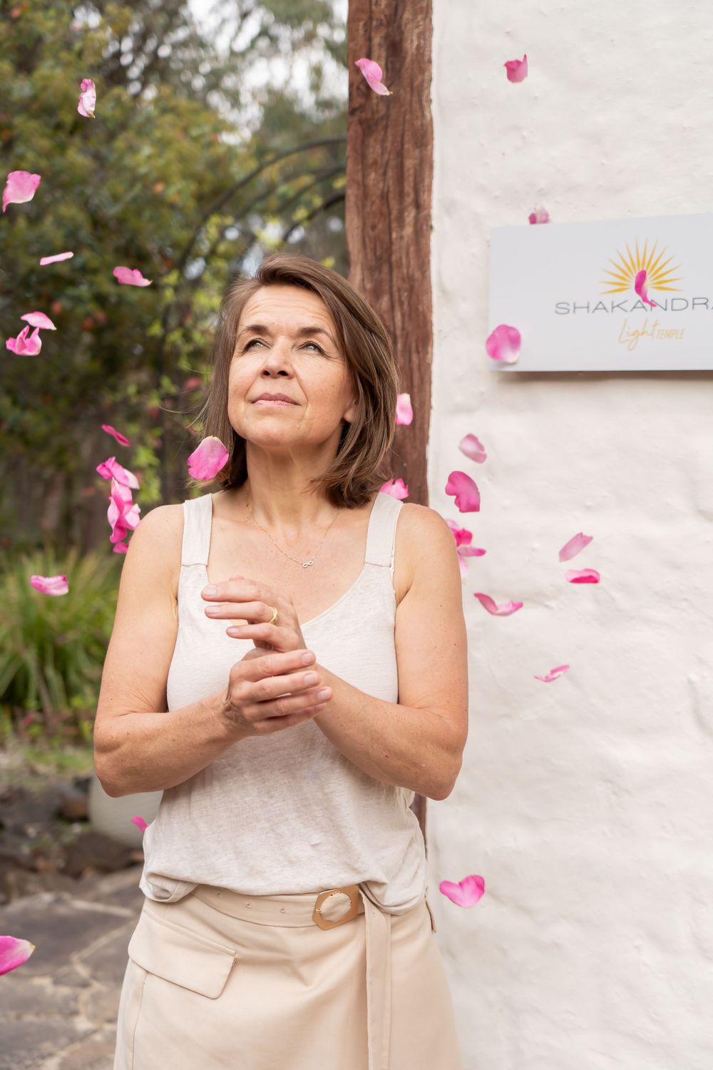 Pink flower petals falling against white wall with spiritual center signage.
