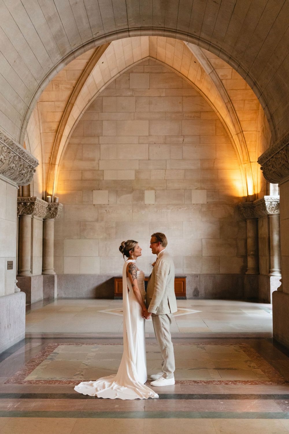 Arched stone corridor with vaulted ceiling and decorative architectural details in warm lighting.