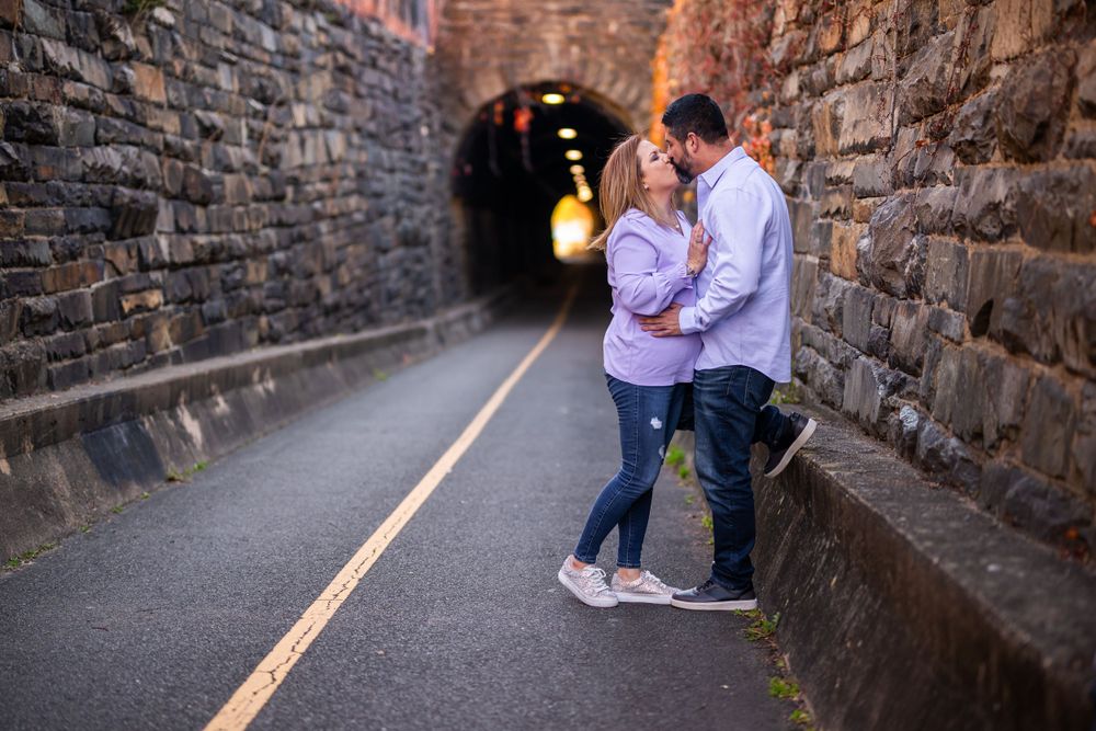 Couple sharing intimate moment in stone tunnel with warm lighting.