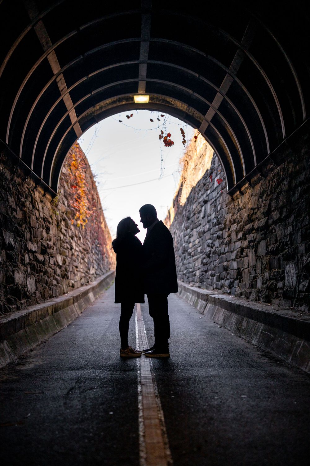 Silhouetted couple sharing intimate moment in dramatic tunnel lighting.
