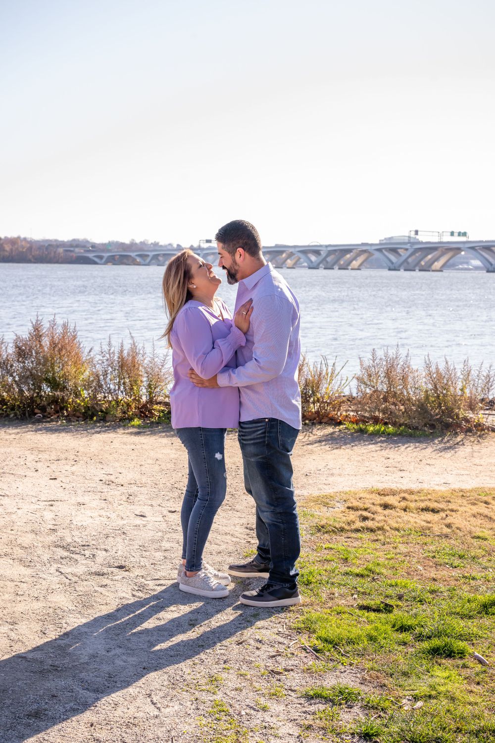 A couple in matching purple and white outfits sharing an intimate moment by the water.