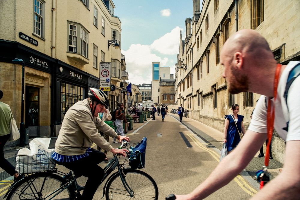 Busy street scene with cyclists and pedestrians along historic buildings in Oxford.