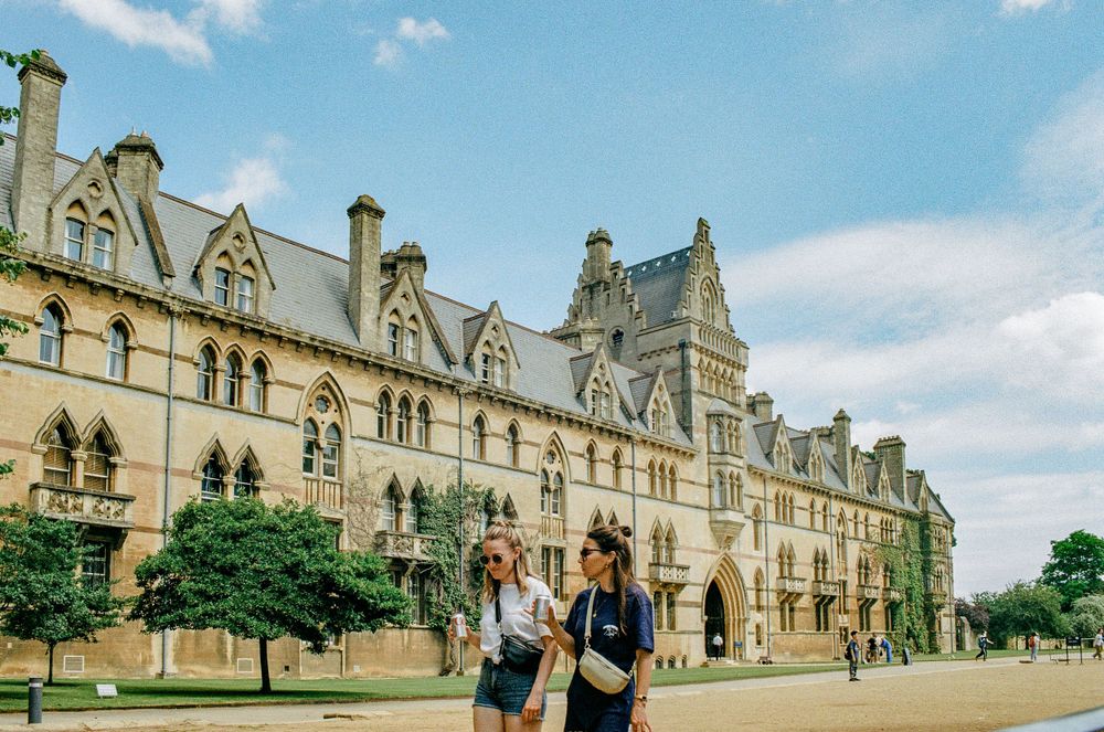 Historic Christ Church College building in Oxford with Gothic architecture and trees along the facade.