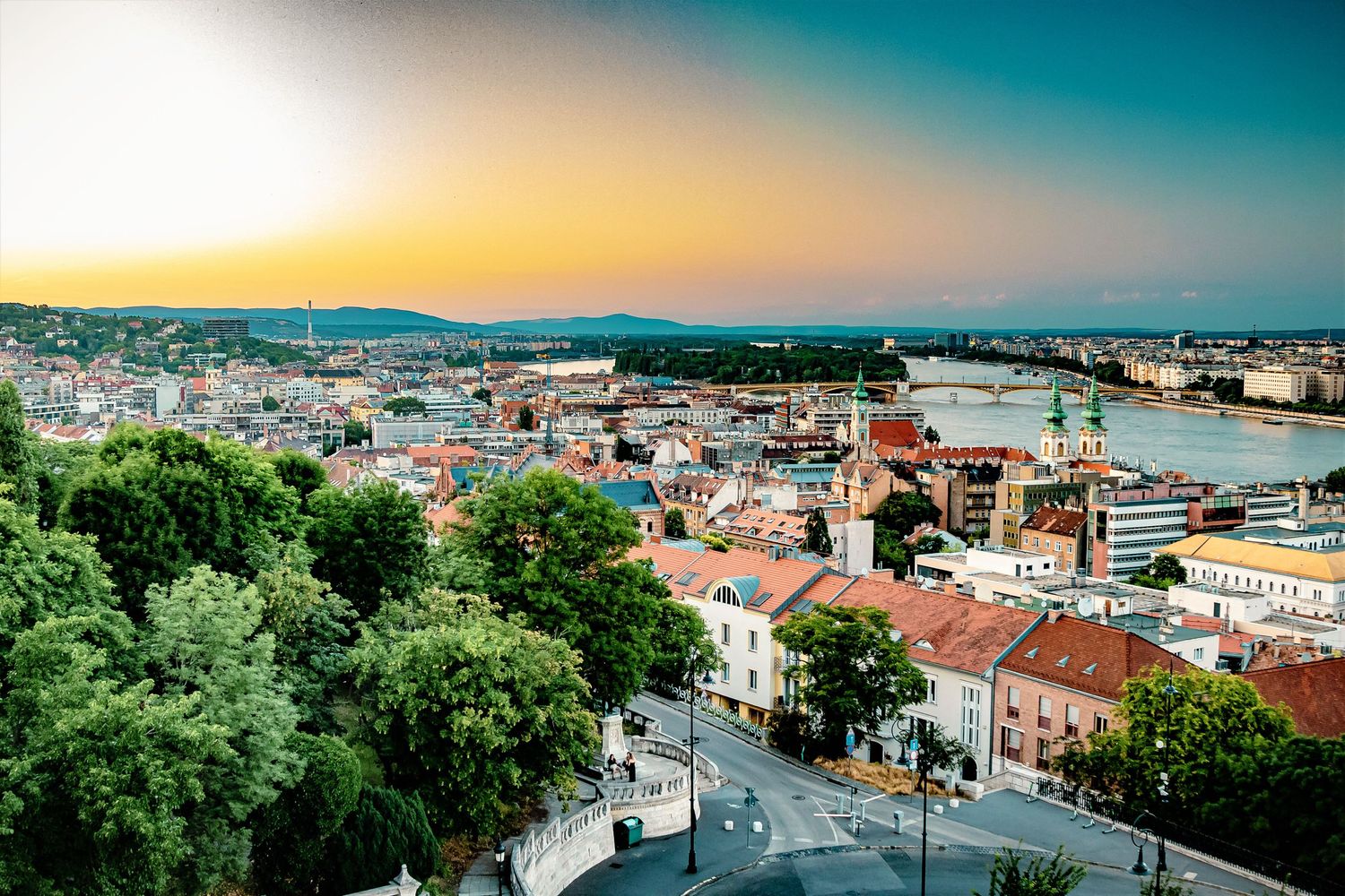 Sunset cityscape of Budapest with historic buildings and river views from elevated perspective.