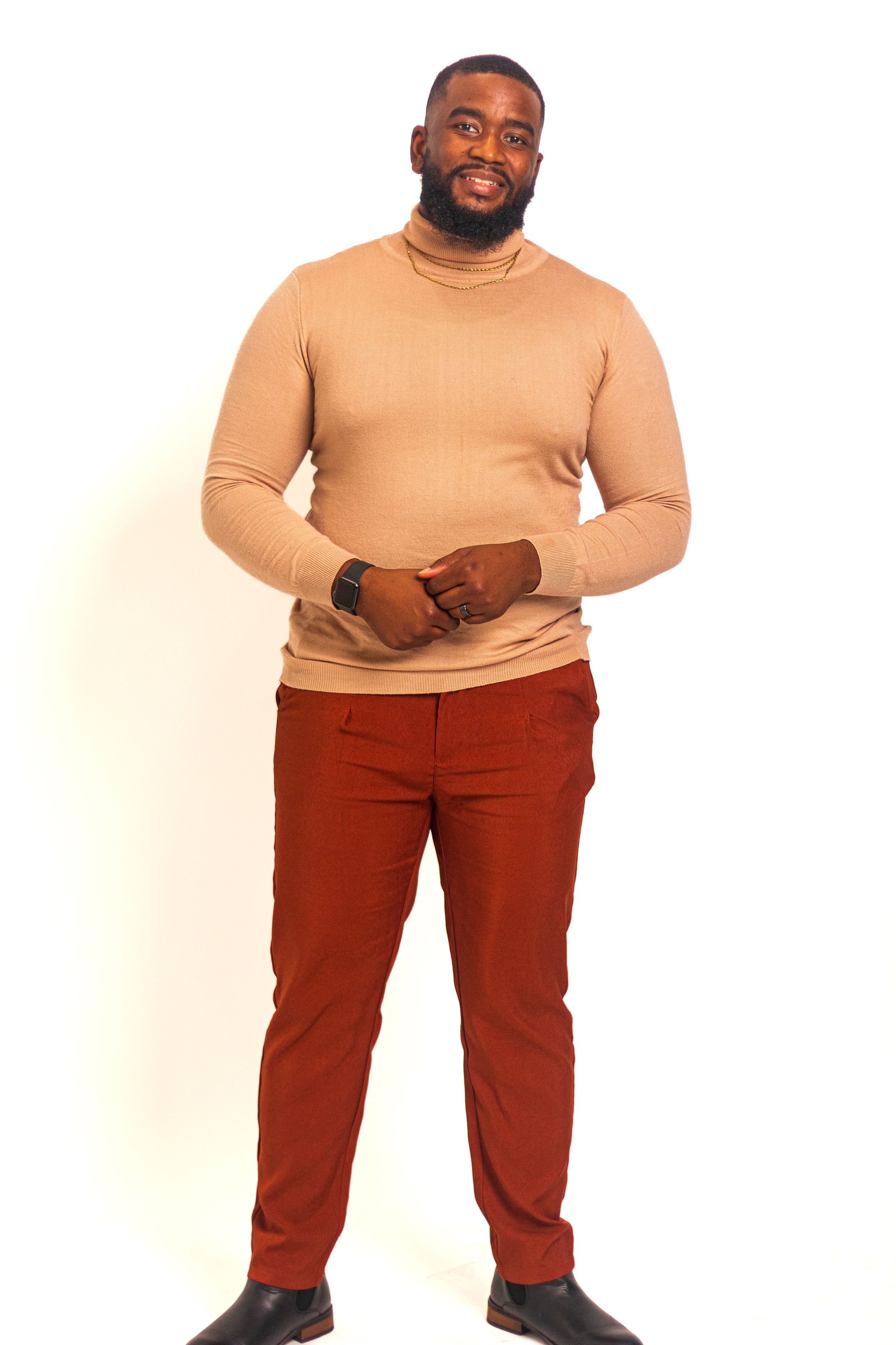 A stylish portrait featuring a tan turtleneck sweater and burgundy pants against white background.