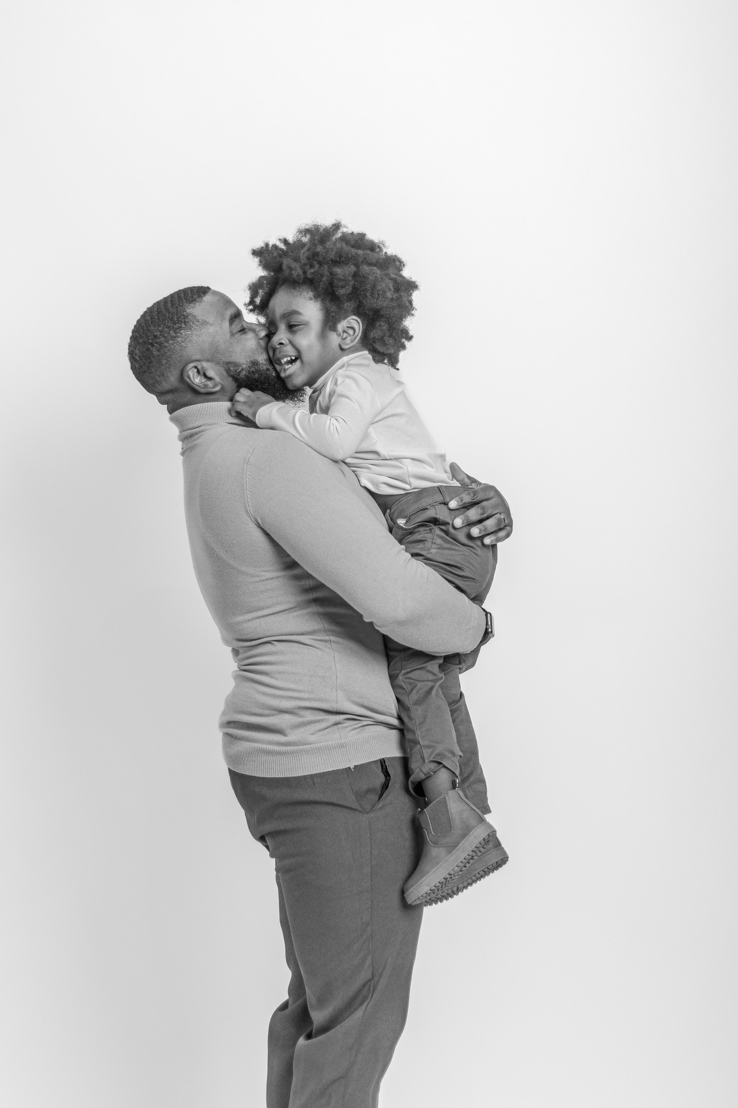 Sweet moment captured in black and white studio portrait showing parent-child embrace.
