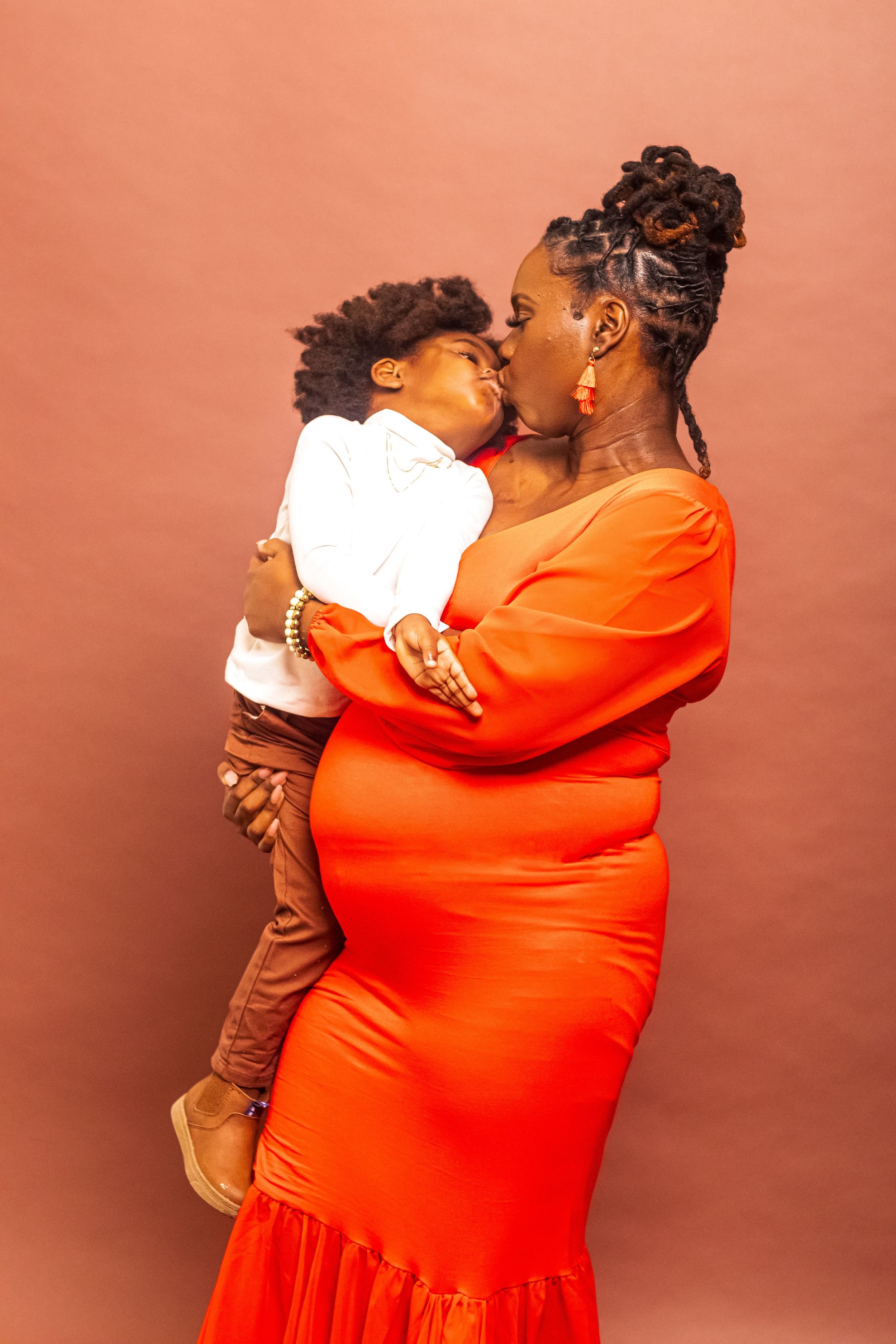 Tender moment between parent and child against coral background with matching outfits.