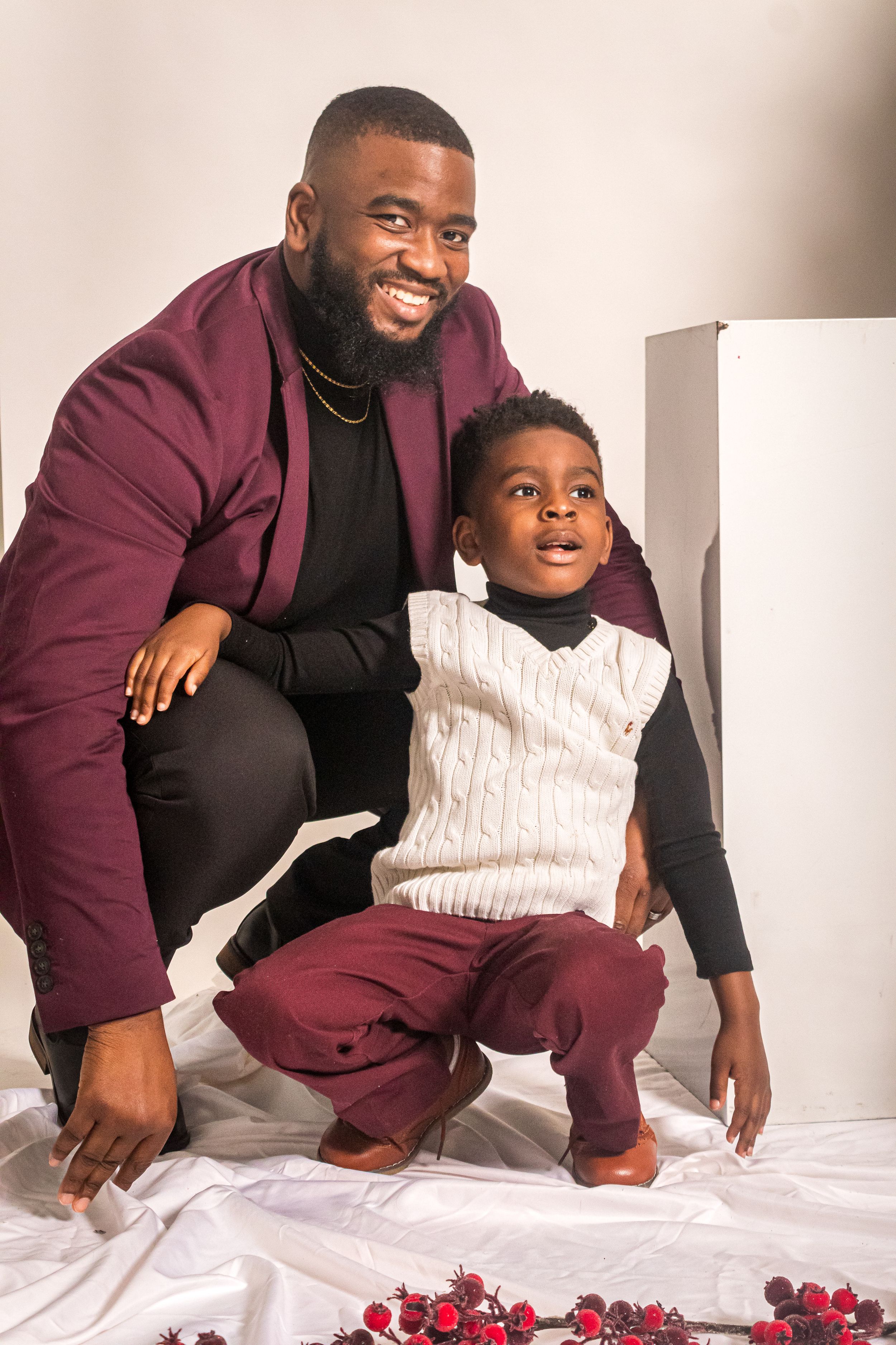 A heartwarming holiday photo showing two people in coordinated burgundy outfits posing by festive red berries.