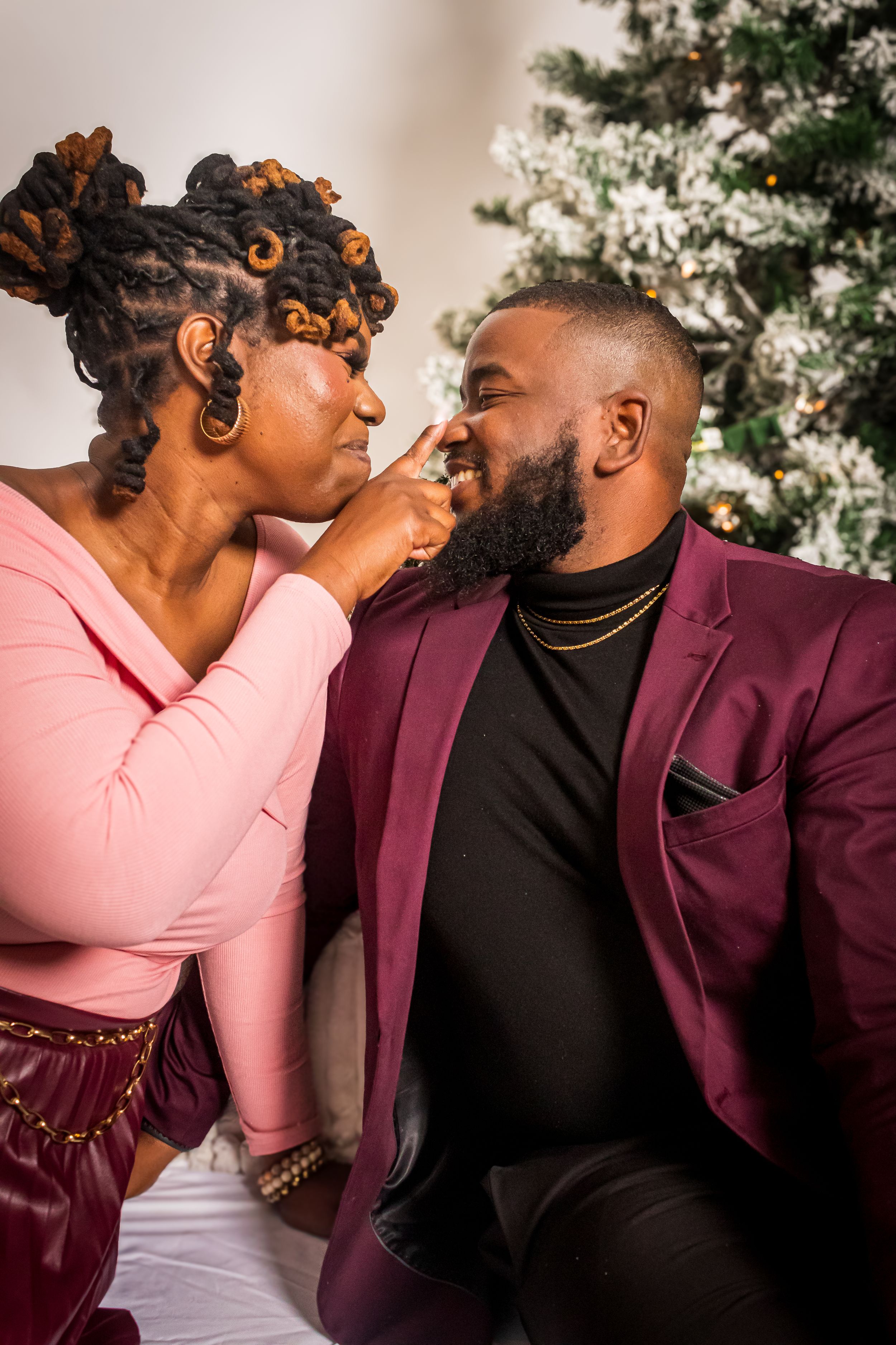 An intimate moment captured in front of a snow-dusted Christmas tree.