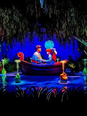 A romantic boat scene illuminated in blue with glowing mystical elements and decorative lighting in a theme park attraction.