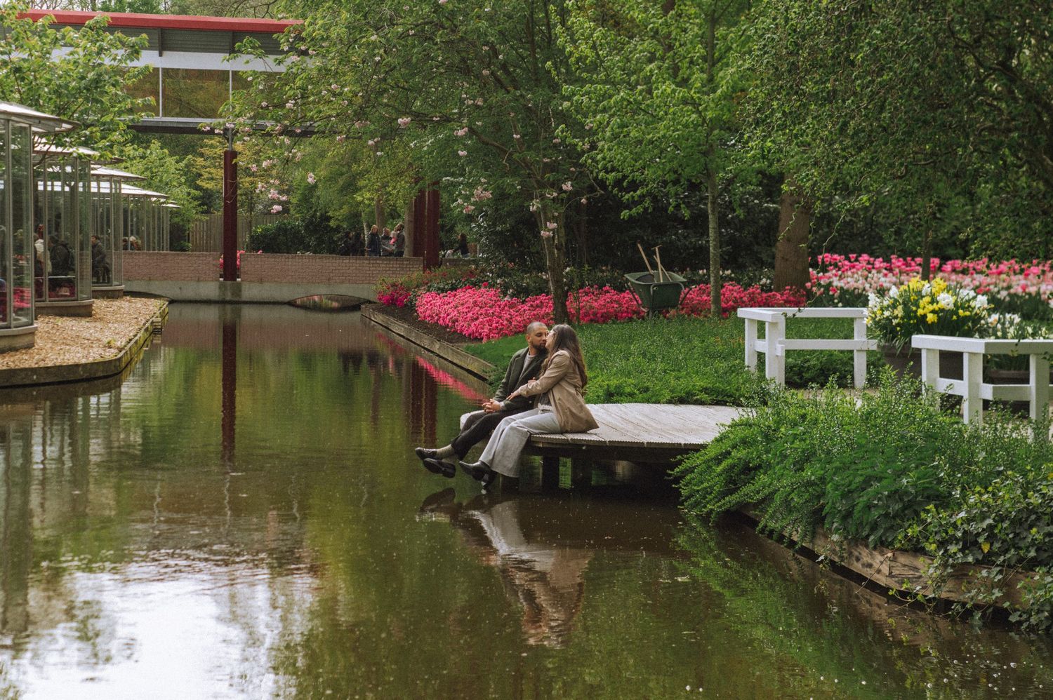 Peaceful pond surrounded by flowering trees and walking paths in a lush garden setting.