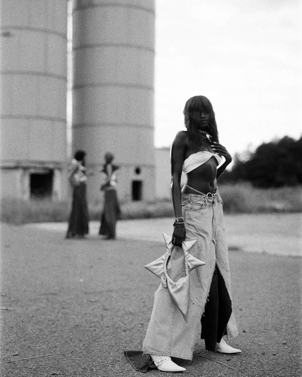 Artistic black and white fashion photo near industrial storage tanks.
