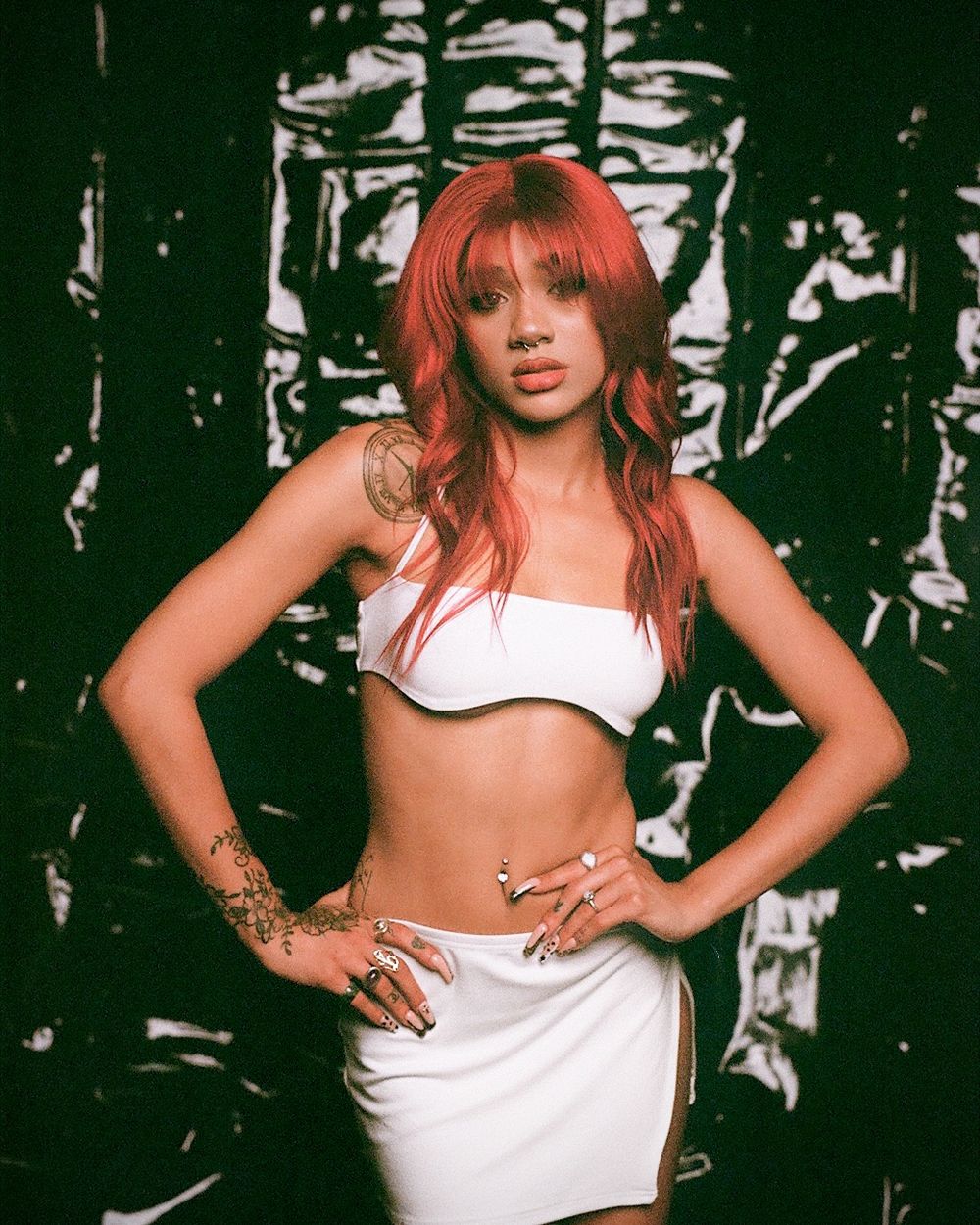 Fashion photo with red hair and white outfit against dark textured background.