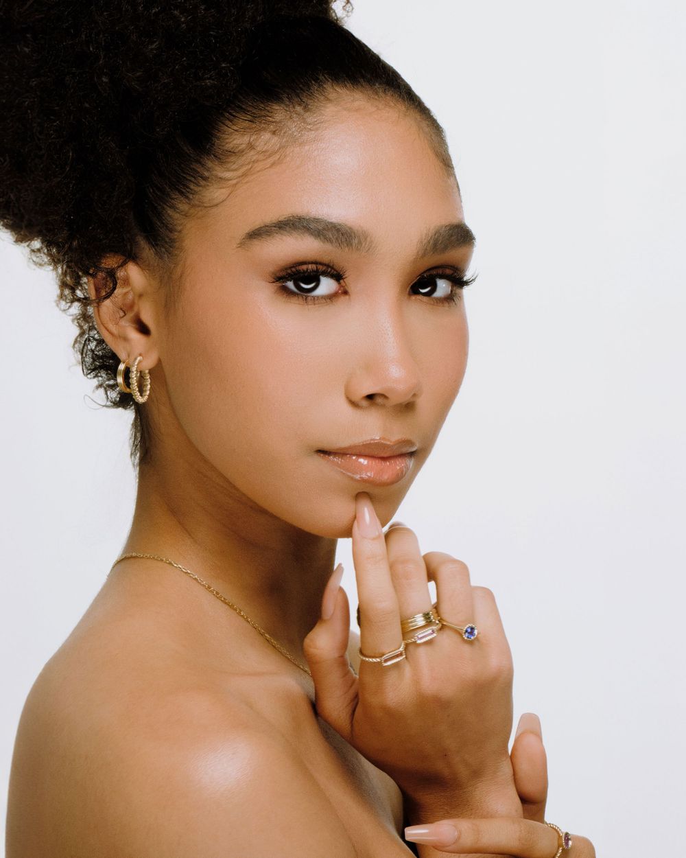 Studio beauty portrait with natural makeup, gold jewelry and an elegant updo hairstyle.
