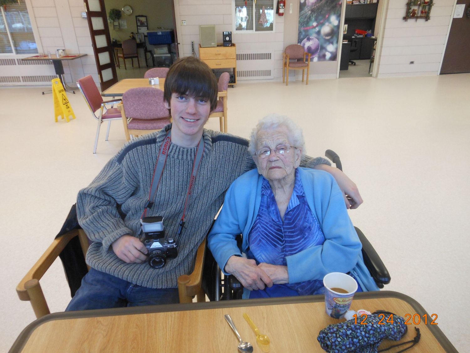 Two people sitting together at a table in what appears to be a community or care facility.