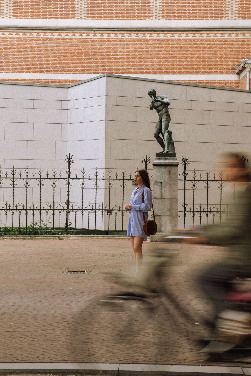 Blurred motion shot of person walking past brick wall with decorative iron fence.