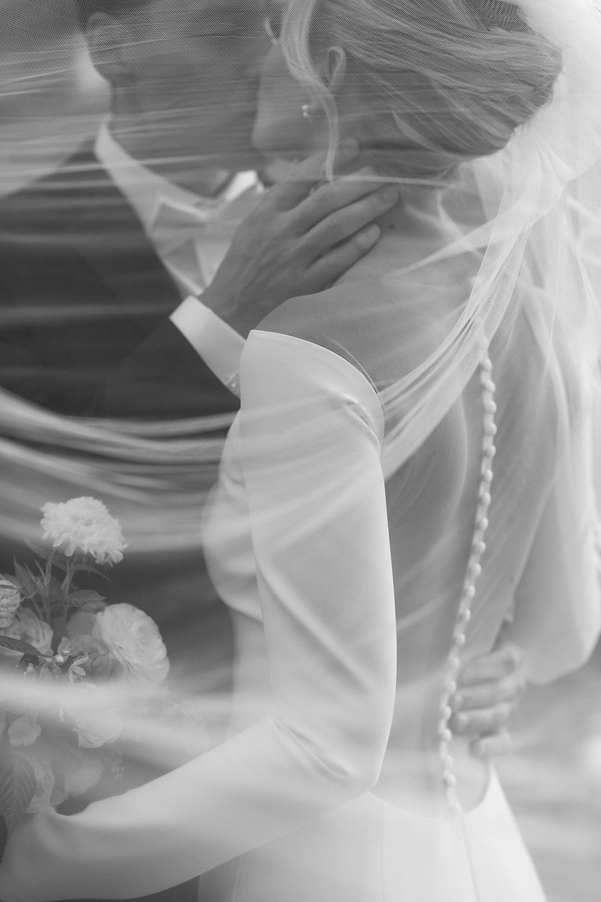 Artistic black and white close-up of bride in long sleeve dress with delicate veil details.