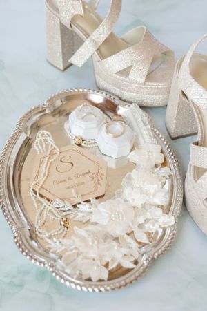 Elegant wedding accessories including sparkly heels and delicate lace details displayed on an ornate silver tray.