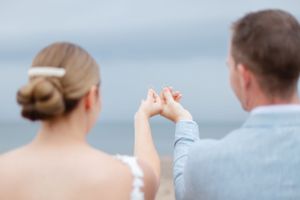 A couple holds hands against a waterfront backdrop in an intimate moment.