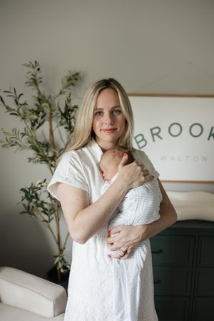 mom holding newborn baby boy on her chest smiling at the camera