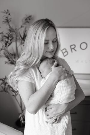 mom holding sleeping newborn baby boy on chest while looking down at hime newborn photography kansas city