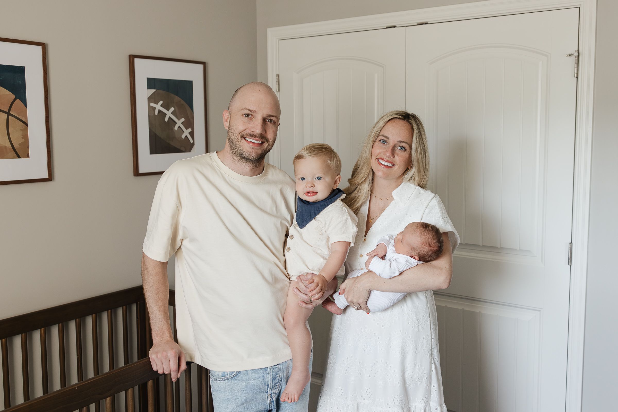 family of four smiling at camera dad holding toddler son mom holding newborn baby boy newborn photography kansas city
