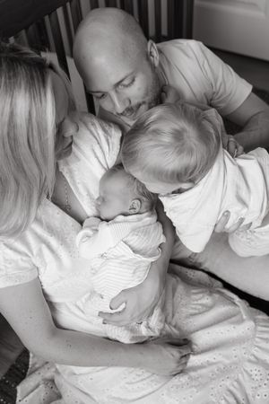 black and white toddler giving sleeping baby brother kiss on head