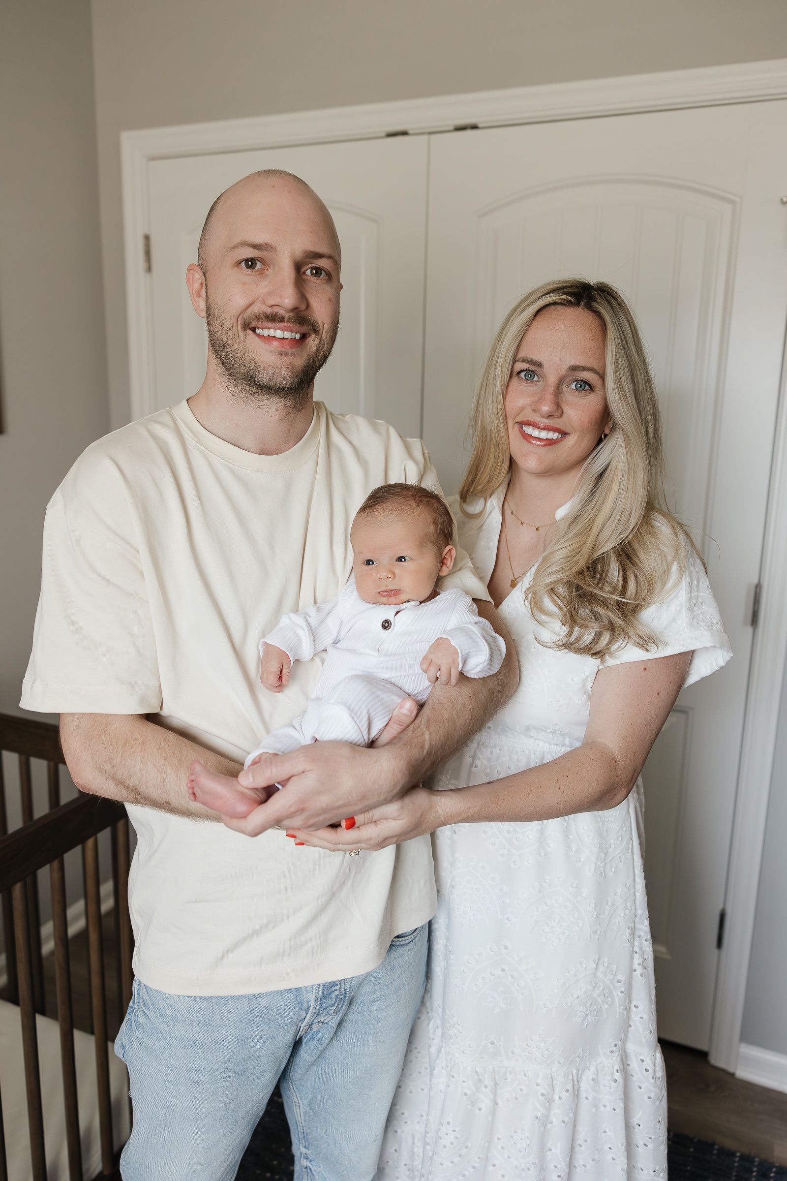 mom and dad holding newborn baby boy smiling at the camera