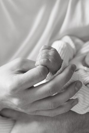 close up of dads hand with baby boy holding index finger newborn photography kansas city