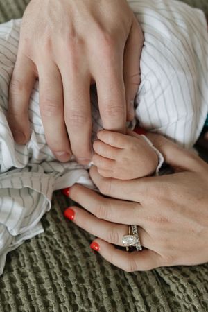 mom and dad holding sleeping babys hand
