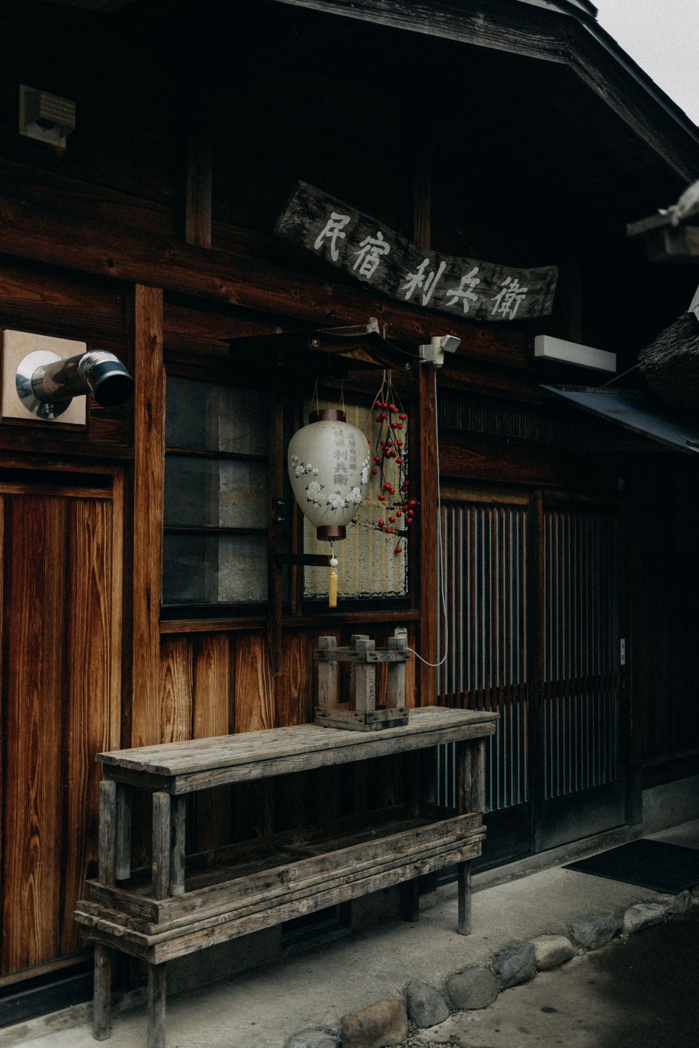 Vintage Japanese storefront with wooden bench and traditional lantern hanging under kanji signage.